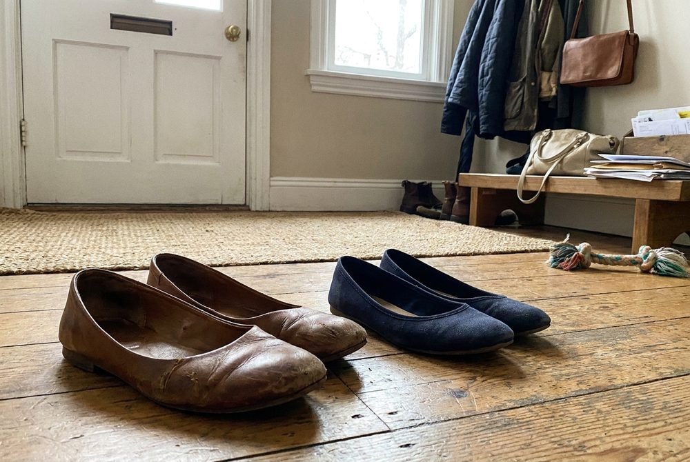 Two pairs of flat shoes left by a front door